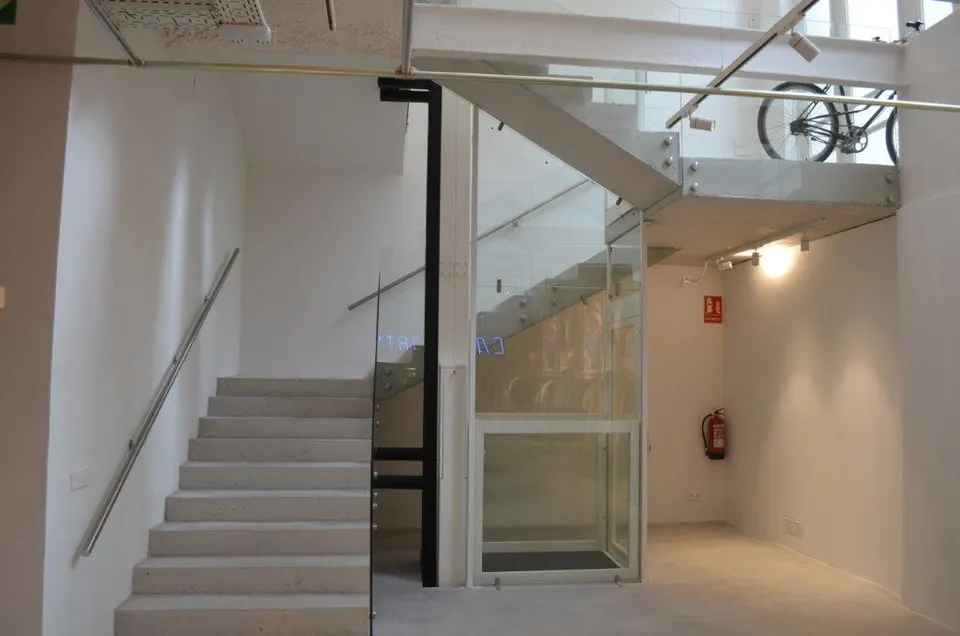 Architectural glass OnLevel platform lift installed beside a concrete staircase