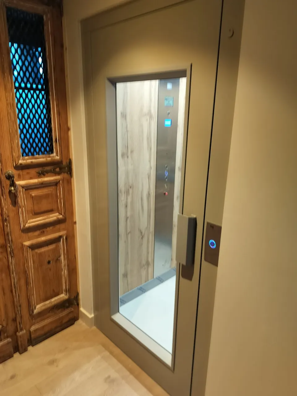 Light oak OnLevel TV300 home lift cabin behind a glazed landing door