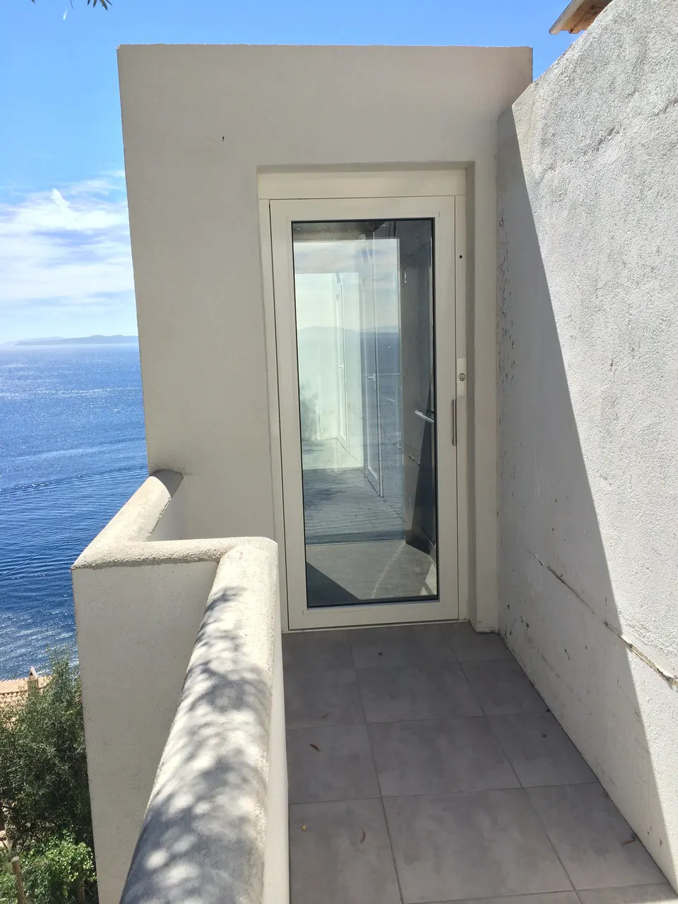 Glass OnLevel lift shaft against stone and timber cladding on a garden deck